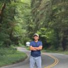 Hamid posing in a road with trees in the background.
